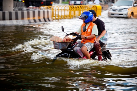 BANGKOK, THAILAND - NOVEMBER 5, 2011 : Two men on a motorbike navigating through the flood after the heaviest monsoon rain in 20 years in the capital on November 5,2011 Bangkok, Thailand.のeditorial素材