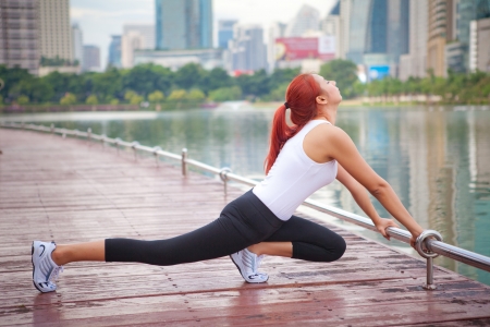 Beautiful young asian woman doing stretching exercise in the cityの写真素材