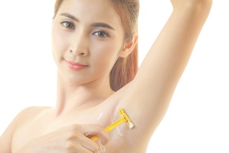 Young asian woman shaving armpit with razor isolated on white backgroundの写真素材