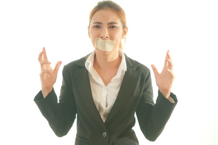 Freedom of speech concept. Young asian woman with tape on her mouth. Isolated on whiteの写真素材