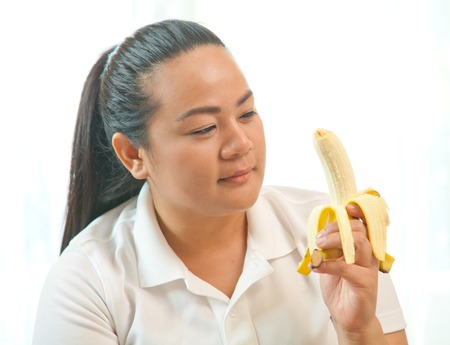 Fat asian woman with banana on whiteの写真素材
