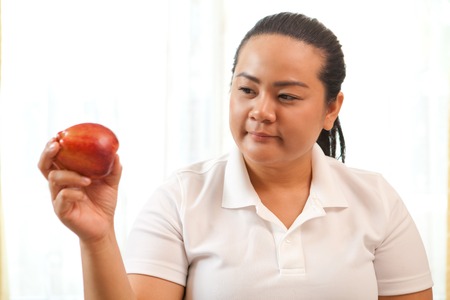 Fat asian woman with apple on whiteの写真素材