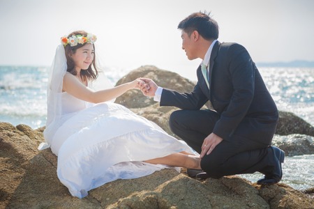 Beautiful asian couple on the beach in wedding dressの写真素材