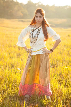 Hippie woman posing in golden field on sunsetの写真素材