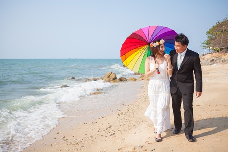 Beautiful asian couple on the beach in wedding dressの写真素材