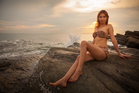 Sexy asian model posing at the stone on sunsetの写真素材