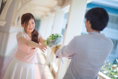 Man ready to give flowers to girlfriendの写真素材