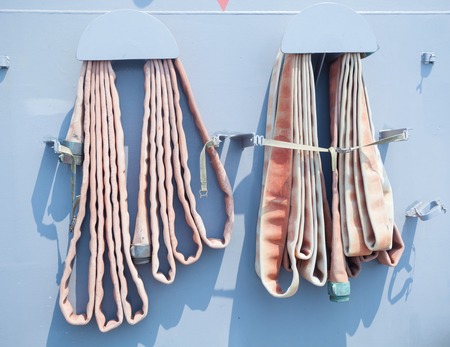 Old fire hose on blue wallの写真素材