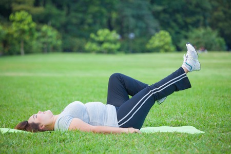 Asian fat woman lying by exercise leg upwards at the parkの写真素材