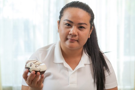 portrait of fat woman eating a donutの写真素材