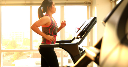 Young asian woman exercising on a treadmill