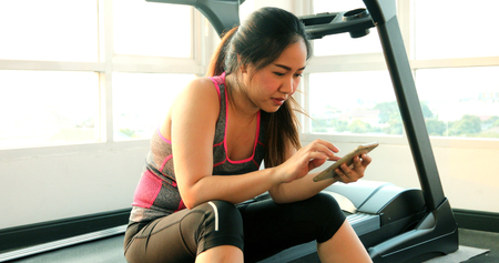 Young asian woman with mobile phone in fitness gym