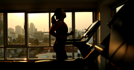 Young asian woman exercising on a treadmillの写真素材
