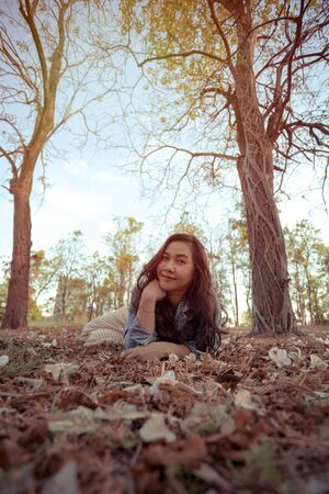 Young asian woman is posing in front of a camera in an autumn parkの写真素材
