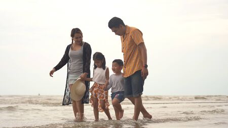 Happy asian family enjoying walk on the beachの写真素材