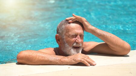 Senior man swimming in an outdoor swimming poolの写真素材