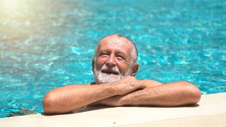 Senior man swimming in an outdoor swimming poolの写真素材