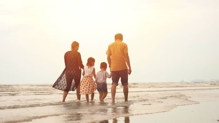Happy asian family enjoying walk on the beachの写真素材