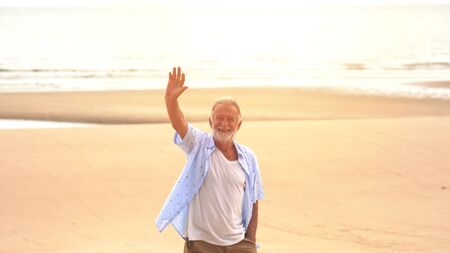 Happy Senior man hand up on the beachの写真素材