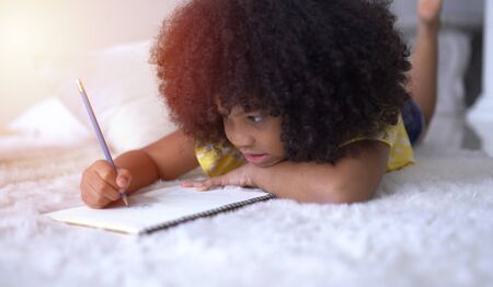 Portrait of cute little African student doing schoolworkの写真素材