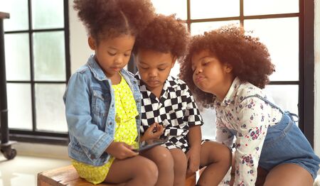 Little cute afro children playing on smartphoneの写真素材