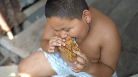 Asisn fat boy eat chicken outdoorの写真素材