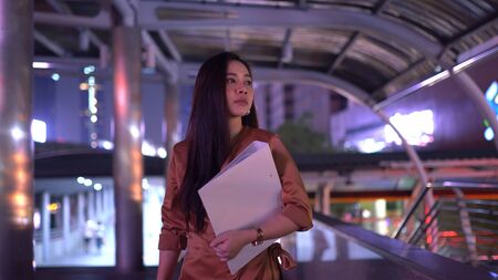 Beautiful young asian woman walking in the night city streetsの写真素材