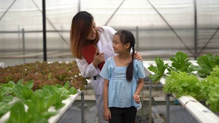 Asian woman and girl learning to grow organic vegetables in the farm