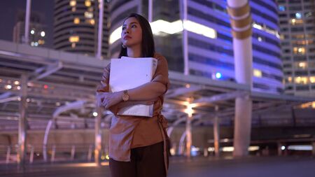 Beautiful young asian woman walking in the night city streetsの写真素材