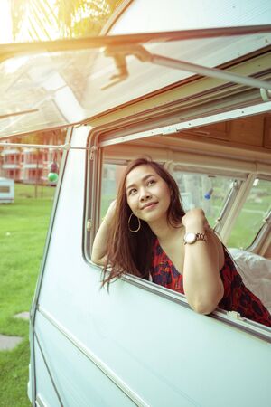 Beautiful young asian woman in a camper van on a summer day