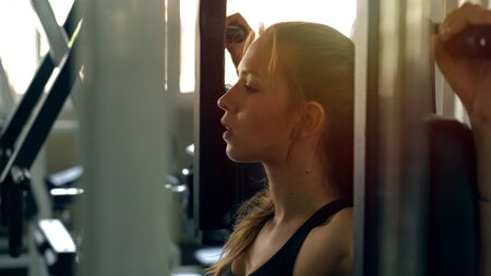 Young beautiful woman doing exercises with weight training in gym