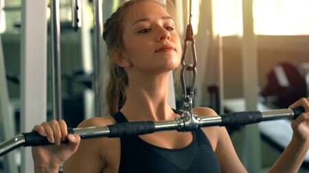 Young beautiful woman doing exercises with weight training in gym