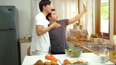 Asian gay couple taking selfie and live streaming at homeの写真素材