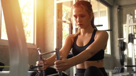 Young beautiful woman doing exercises with weight training in gym