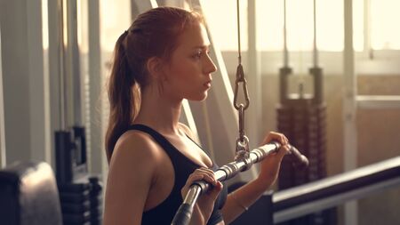 Young beautiful woman doing exercises with weight training in gym