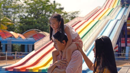 A happy family of mother, father and children, daughter, having fun on vacation at a water park