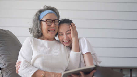Asian senior woman and daughter reading a book at home