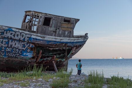 An old wooden fishing boat covered in graffiti on dry dock.