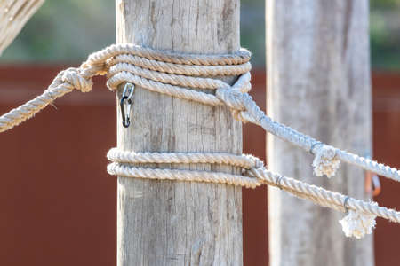 White rope with shackles wrapped around a large wooden poleの写真素材