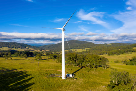 Aerial view of a large three blade industrial wind turbine generating electricity in a wind farm