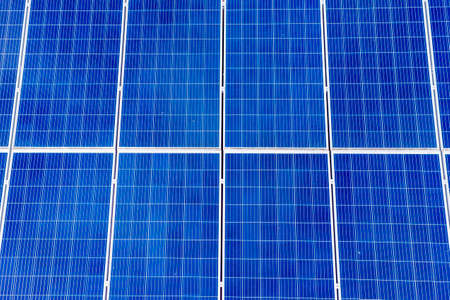 Aerial view of large blue solar panels on a building roofの写真素材