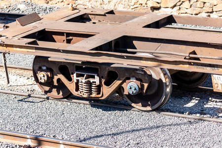 Old and rusty train wheels on a flat bed carriage sitting idle on railway tracks at a production...