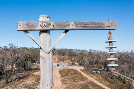 Drone aerial photograph of a telephone pole and wires in a forest affected by bushfires