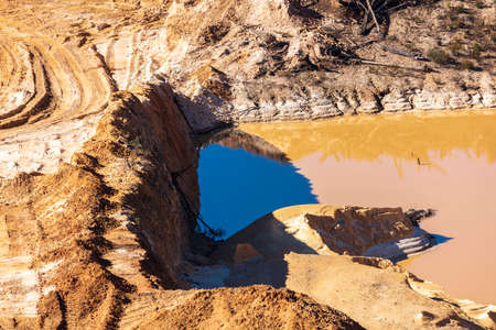 Photograph of stagnant flood water lying on the ground in a large quarryの写真素材