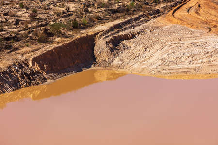 Photograph of stagnant flood water lying on the ground in a large quarryの写真素材