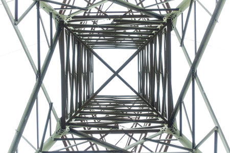 Photograph looking up internally through a large steel electrical transmission tower against a grey...