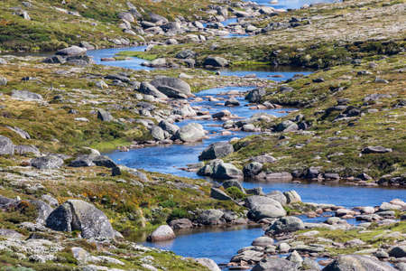 Photograph of a fresh water river flowing through a green rocky valley in the Snowy Mountains in New South Wales in Australiaの写真素材