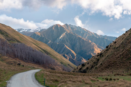 Photograph of a large mountain range on a winding road in Moke Lake Reserve near Queenstown on the South Island of New Zealandの写真素材
