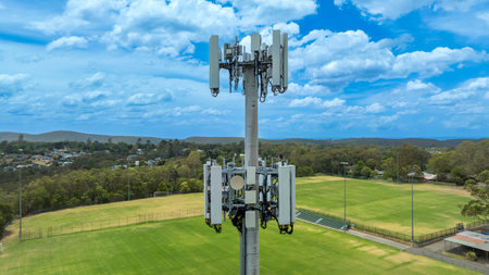 Drone aerial photograph of the top section of a telecommunications tower equipped with antennas and...