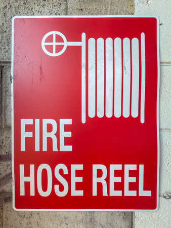 Photograph of an old and dirty red coloured metal Fire Hose Reel sign located on a dirty wall...